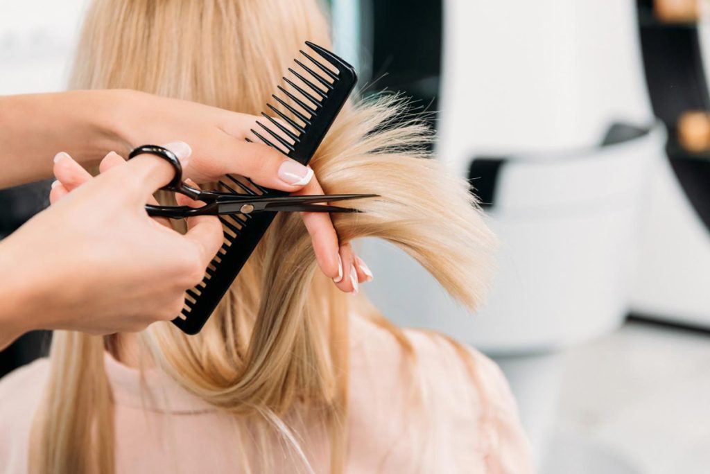 Hairstylist combing and cutting the hair of a woman
