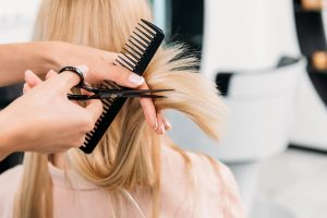 Hairstylist combing and cutting the hair of a woman