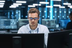 A focused system administrator looks at the screen in a data centre.