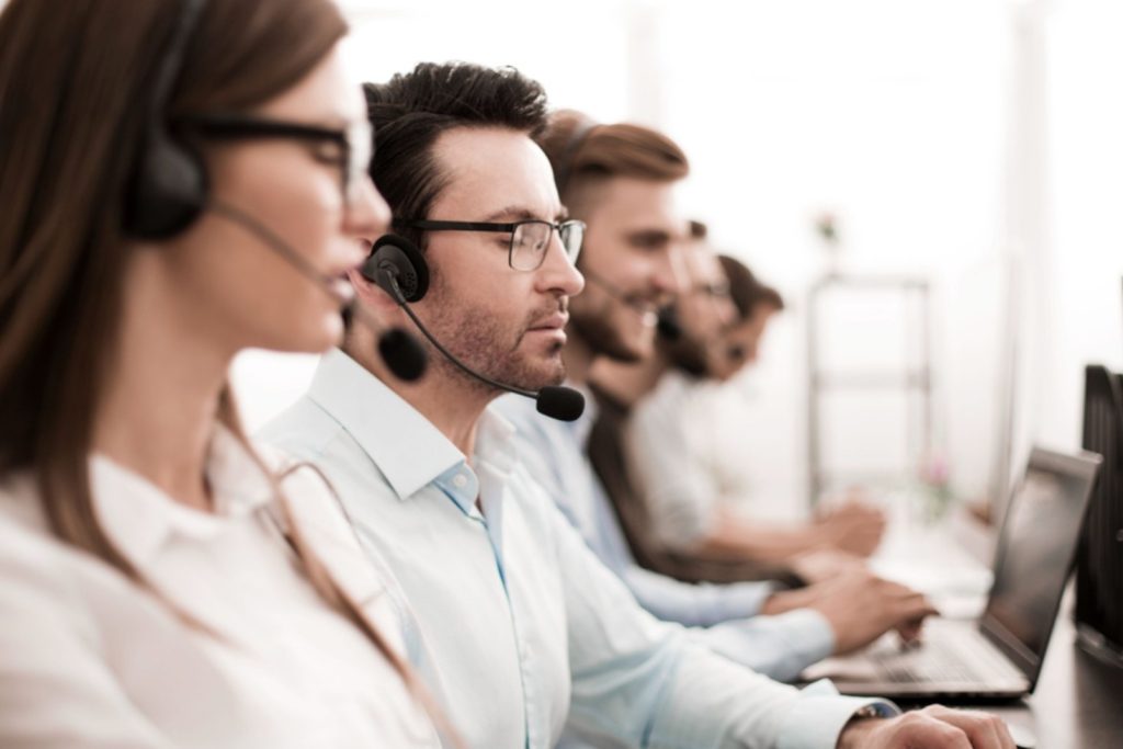 Close up of people in front of computers with headsets.