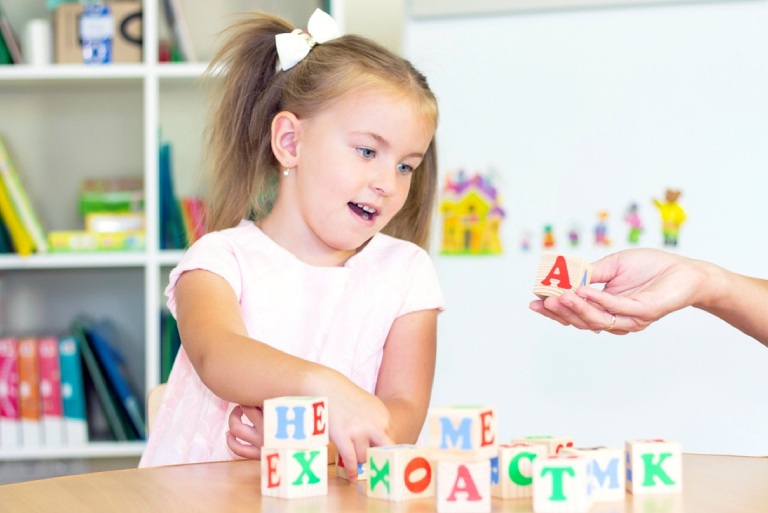 Little girl sounding out letters. Speech therapy exercises and games with letters.