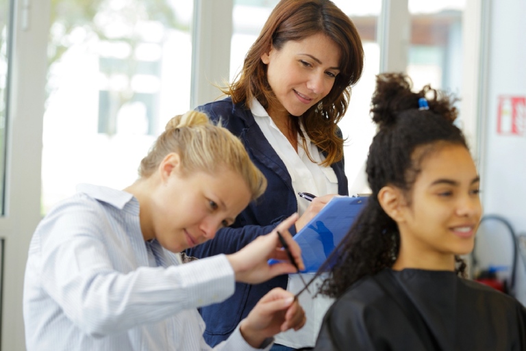 Professor assessing trainee hairstylist.